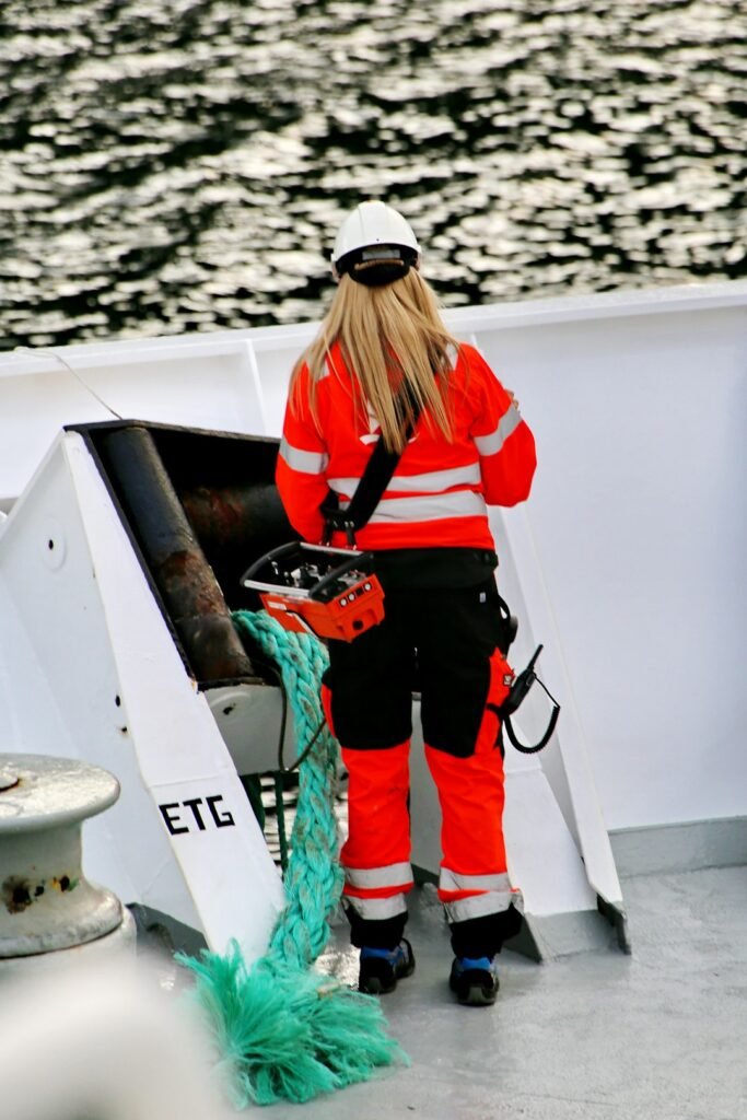 A woman working on deck of a coastal transport vessel in polar region of Norway; same job as for male colleagues on a big ship with heavy weather and equipment.Equal job = equal pay.