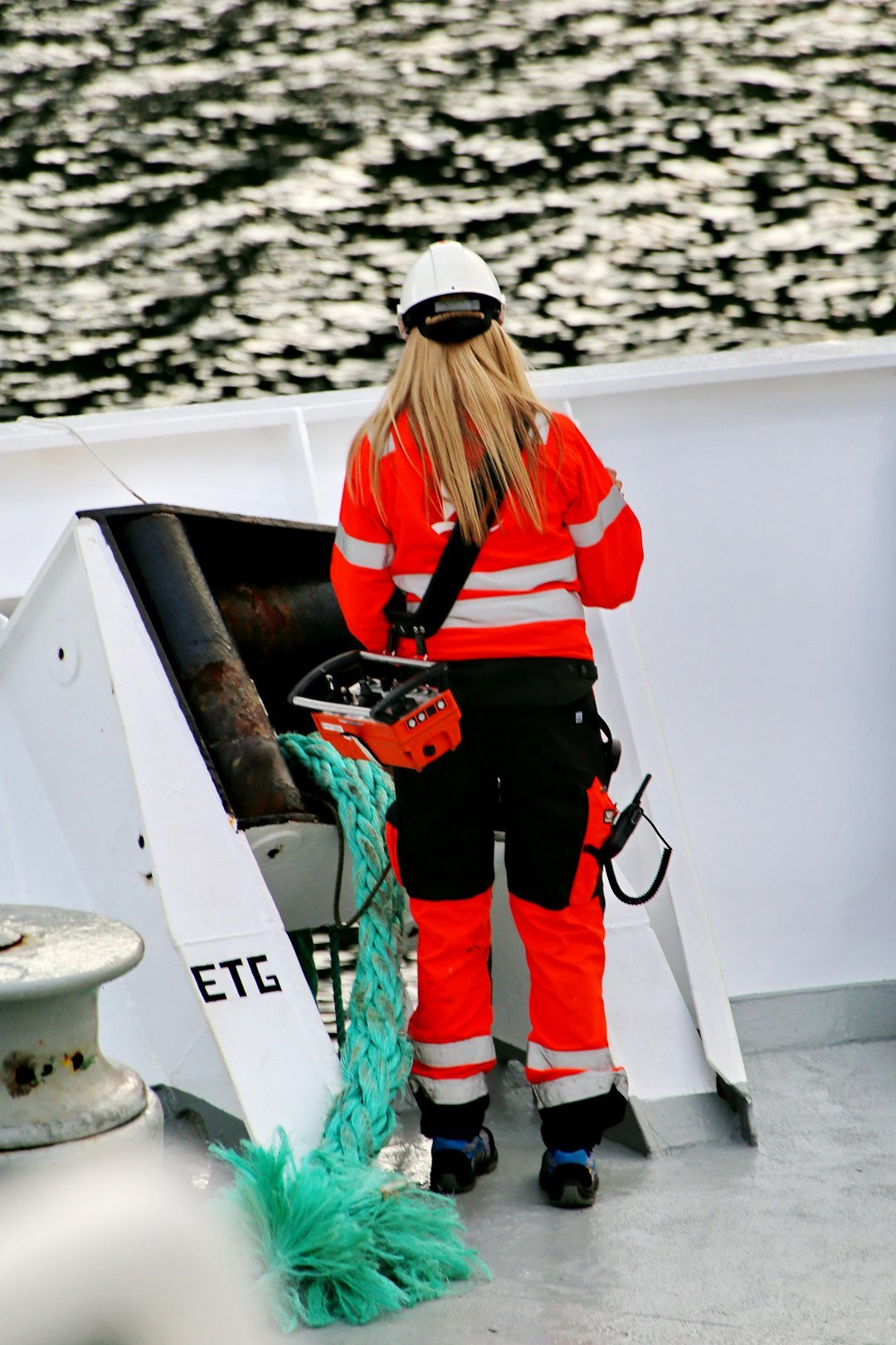 A woman working on deck of a coastal transport vessel in polar region of Norway; same job as for male colleagues on a big ship with heavy weather and equipment.Equal job = equal pay.